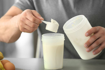 Sporty man making protein shake at home, closeup