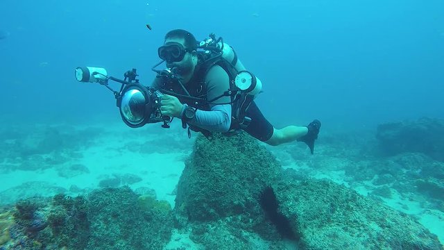 A video of an underwater cameraman taking photos of marine life in the ocean with underwater equipment and lights
