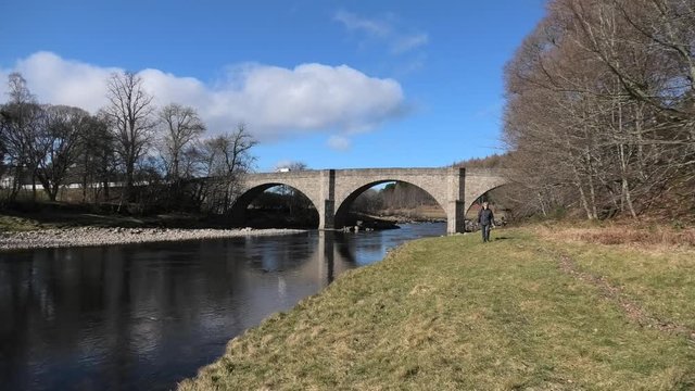 Potarch Bridge lady walks to camera in bright spring sunshine