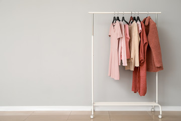 Rack with stylish clothes near grey wall