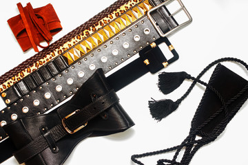 Collection of women's trendy leather belts on white background. Women's fashion accessories. Different types of waistbands and leather corset. Flat lay, top view.