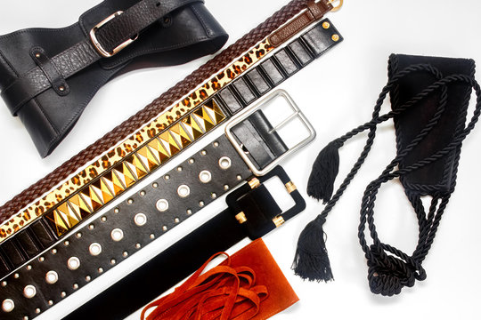 Collection of women's trendy leather belts on white background. Women's fashion accessories. Different types of waistbands and leather corset. Flat lay, top view.