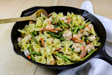 Freshly made bowtie pasta with asparagus and shrimp in a cast iron pan