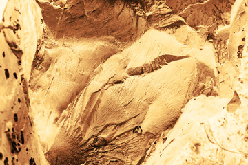 Vintage yellow background. Rough painted wall of aspen gold color. Imperfect plane of golden colored. Uneven old decorative toned backdrop of yellow tint. Texture of gold hue. Ornamental stony surface