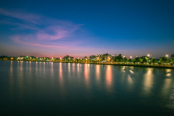 Fototapeta premium The background of the white light in the evening on the lake, with blurred lights from the waterfront shelter, with the wind blowing all the time, people exercising for health.