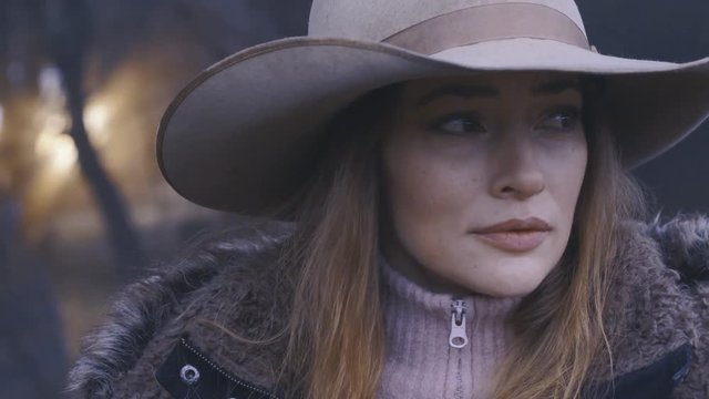 Close up of a cowgirl in the woods, looking around her for wild animals to hunt, earth tones, 60 fps.