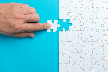 Hand putting the last piece of white puzzle for business concept or content background