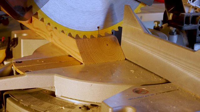 Using a miter saw to cut a wood plank 2X4 - close up