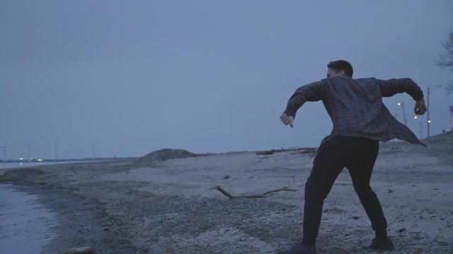 Caucasian Man Skipping Rocks At A Cold Lake