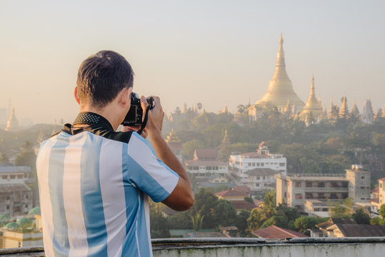 Back view of Asian photographer taking photos of Shwedagon pagoda one of the most famous pagodas in the world and it is certainly the main attraction of Yangon.