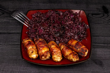 Fried homemade grilled sausages or chevapchichi with stewed sauerkraut on a wooden rustic background