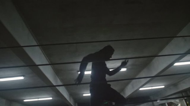 African American male running in a parking garage and jumping a fence in slow motion
