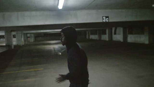 African American male running away in a parking garage