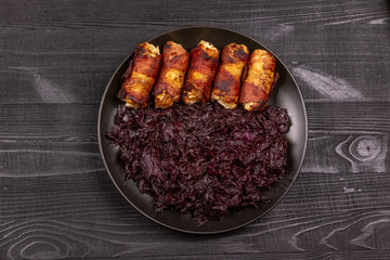 Fried homemade grilled sausages or chevapchichi with stewed sauerkraut on a wooden rustic background.