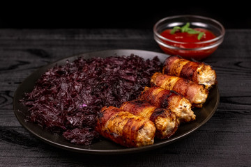 Fried homemade grilled sausages or chevapchichi with stewed sauerkraut and tomato sauce on a wooden rustic background
