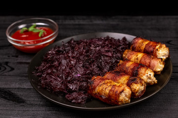 Fried homemade grilled sausages or chevapchichi with stewed sauerkraut and tomato sauce on a wooden rustic background