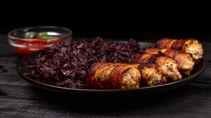 Fried homemade grilled sausages or chevapchichi with stewed sauerkraut and tomato sauce on a wooden rustic background