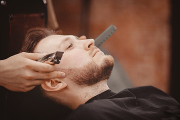 Barber shaves beard of client man on chair Barbershop