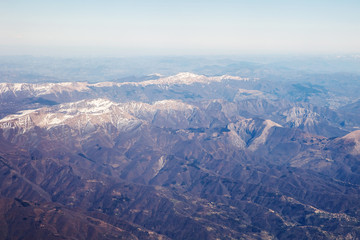 Fototapeta na wymiar Photo from window of wing airplane flying over Alps mountains. Travel concept
