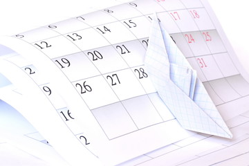 Origami paper boat rises to top on the sheets of monthly calendar folded like high stormy waves on white background. Isolated