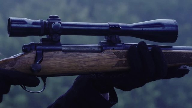 Close up side view of a person holding an armed rifle at night, 30 fps.