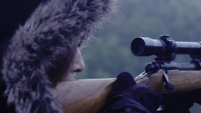Close up side profile of a person holding a weapon, focussed on their target, 23.98 fps.