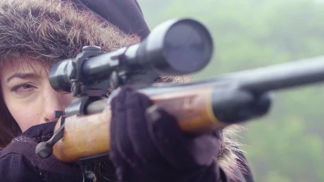Close up of a woman patiently waiting and watching through the telescopic scope of a rifle, 23.98 fps.