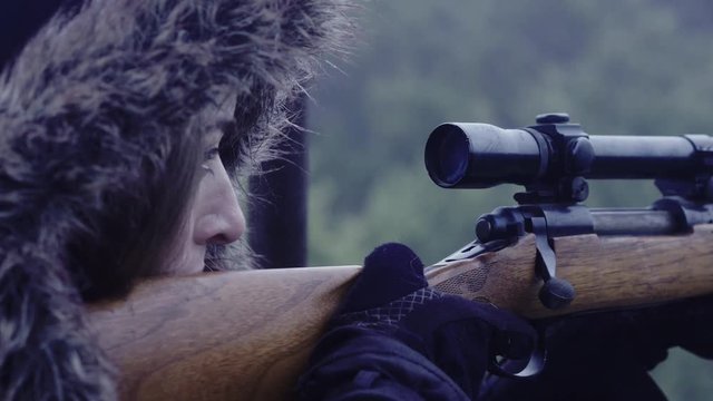 Close up of a person holding a rifle, focussed on their target, 23.98 fps.