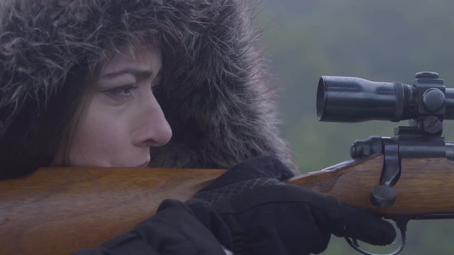 Close up side profile of a woman holding a weapon, focussed on her target, 23.98 fps.