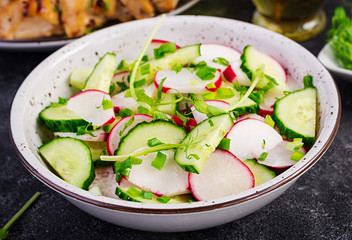 Fresh vegetable  radish and cucumber salad with green onions and microgreens peas on a dark background. Healthy food.