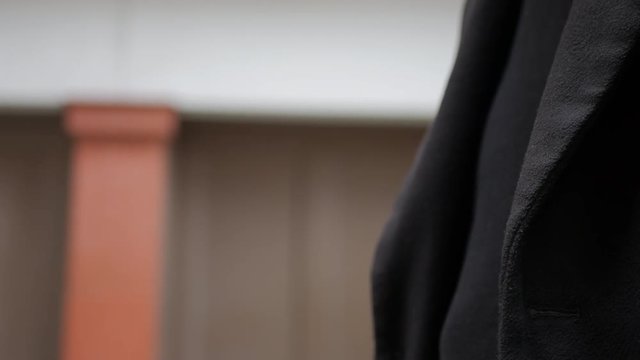Man's right hand raising a black smartphone and then lowering it out of frame