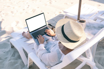 Top view mockup image of a woman holding and using laptop computer with blank desktop screen while...