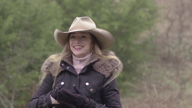 A very happy cowgirl with long hair, dressed up for winter out on the farm.