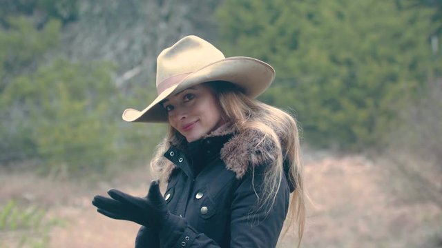 A cowgirl adjusts her gloves and brushes her long hair out of her eyes, 29.97 fps.
