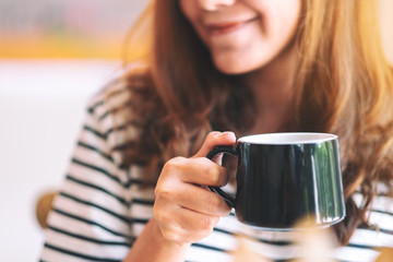 Closeup image of a beautiful woman holding a green cup of hot coffee to drink