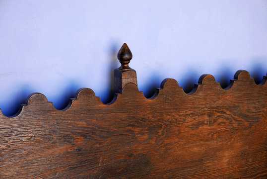wavy top of wooden bench in front of blue wall