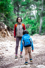 A woman walks with her son through the forest.