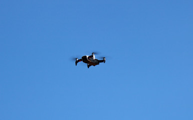 drone quadcopter with digital camera, drone hovering in a bright blue sky