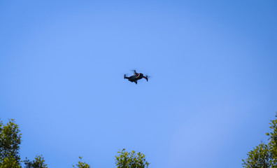drone quadcopter with digital camera, drone hovering in a bright blue sky