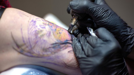 Tattoo master makes a client a colorful tattoo