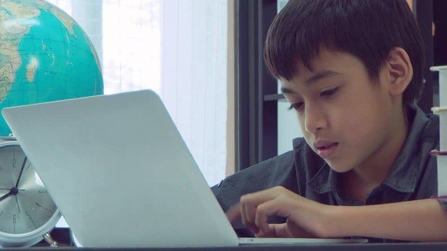 Young asian boy using notebook computer at school