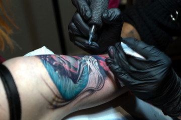 Fototapeta na wymiar Tattoo master makes a client a colorful tattoo