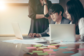 Group of young business people working, communicating at the office desk together with colleagues. Business people has strategic planning with laptop computer in office. Business concept.