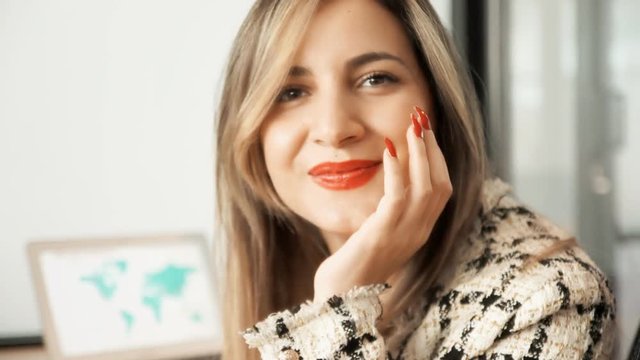 A woman wearing an elegant dress, working on a world map with a laptop, turning towards the viewer and confidently smiling. Slow motion shot.