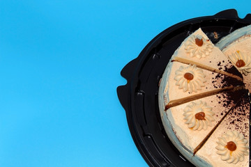 Biscuit cream caramel cake in a brown substrate on a blue background