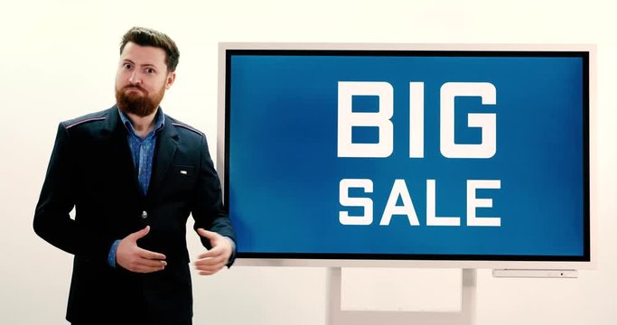 A well dressed caucasian male pointing to a television screen that reads "Big Sale" - perfect for grabbing the attention of your customers.