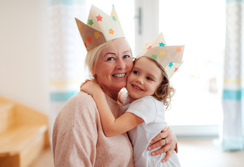 A portrait of small girl with grandmother hugging at home.