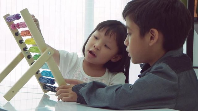 Little asian girl playing with colorful wooden abacus with a boy