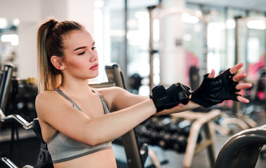 Young girl or woman putting on gloves in gym.