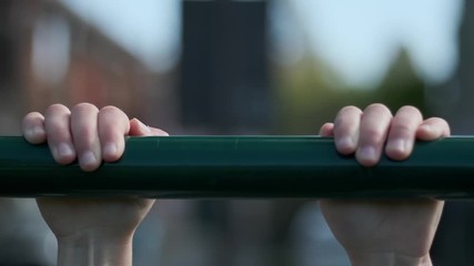 Slow motion close-up as a child hangs on to a metal bar and then lets go.